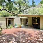 real estate house with flat roof, large windows, and beige siding