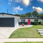 real estate house with gray and white exterior, a red door, and garage